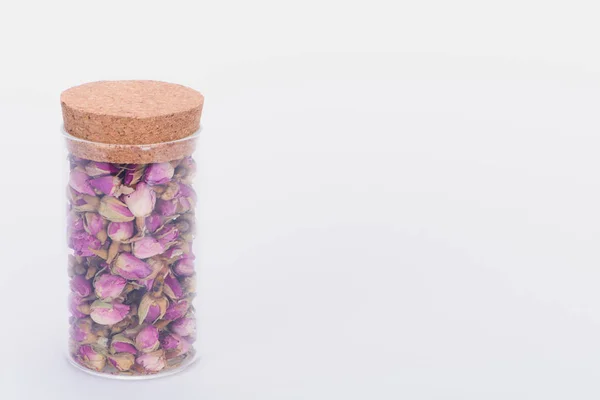 Close-up view of dry rose buds in glass jar isolated on white — Stock Photo