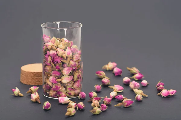 Vista de cerca de hermosos capullos de rosas secas en frasco de vidrio en gris - foto de stock