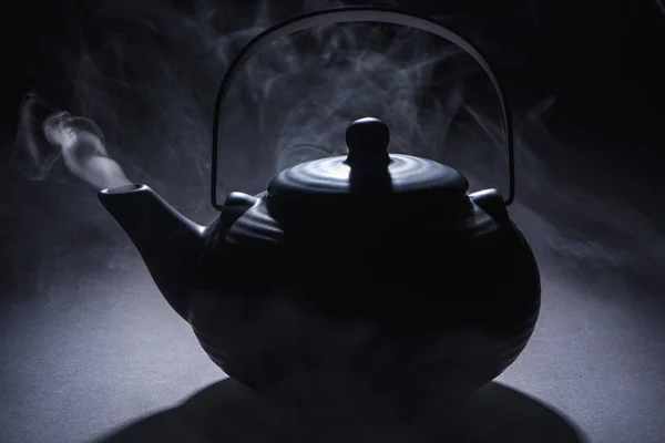 Close-up view of black chinese teapot with hot steam on black — Stock Photo