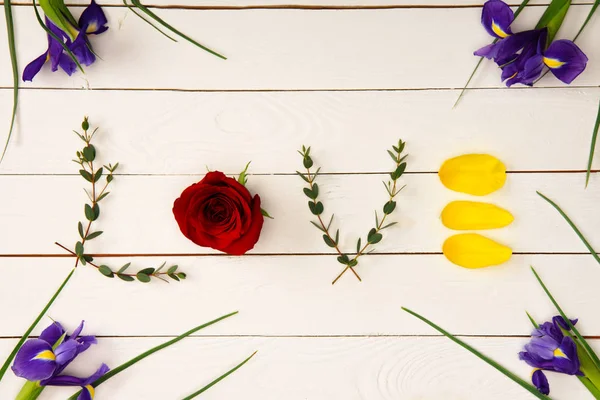 Верхний вид слова любовь из цветочных элементов и красивые цветы радужной оболочки на деревянной поверхности — стоковое фото