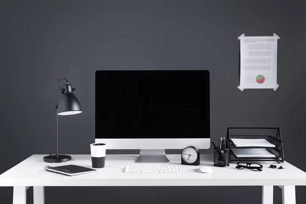 Computadora de escritorio con pantalla en blanco, carta de negocios, reloj y suministros de oficina en el lugar de trabajo - foto de stock