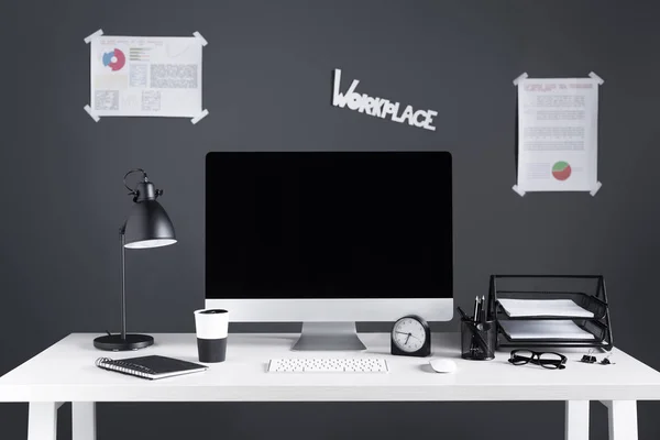 Desktop computer with blank screen, business charts and office supplies at workplace — Stock Photo