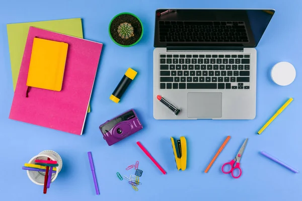 Vue du dessus de l'ordinateur portable avec écran vierge et fournitures de bureau sur bleu — Photo de stock