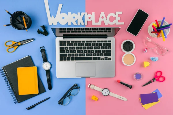Top view of laptop, smartphone, inscription workplace and cosmetics with office supplies divided at male and female workplace — Stock Photo