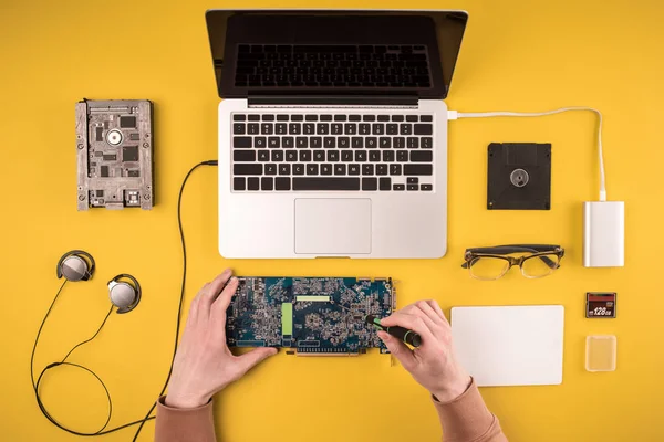 Visão superior parcial da pessoa que fixa o computador portátil no amarelo — Fotografia de Stock