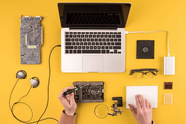 Tiro recortado da pessoa que fixa o computador portátil no amarelo — Fotografia de Stock