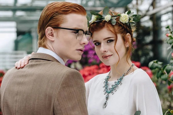 Beau élégant jeune couple de mariage aux cheveux roux debout ensemble dans le jardin botanique — Photo de stock