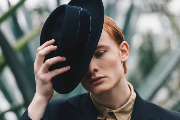 Pensivo bonito jovem ruivo homem vestindo chapéu preto — Fotografia de Stock