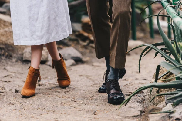 Seção baixa de jovem casal elegante andando juntos no jardim botânico — Fotografia de Stock