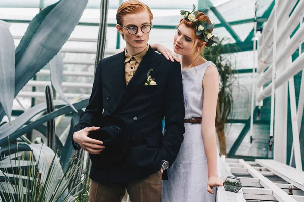 Schönes stylisches junges Hochzeitspaar steht zusammen im botanischen Garten — Stockfoto
