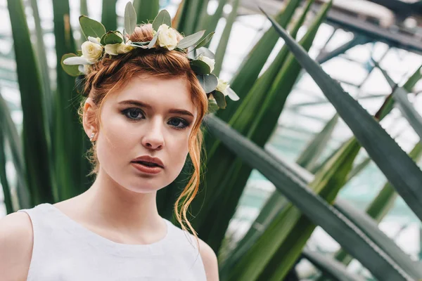 Portrait of beautiful redhead girl in floral wreath looking at camera — Stock Photo
