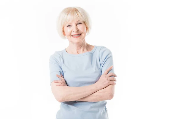 Lächelnde Seniorin mit verschränkten Armen auf weißem Grund — Stockfoto