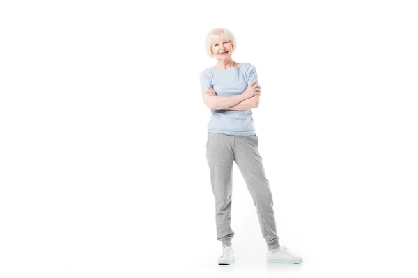 Усміхнена старша спортсменка стоїть з схрещеними руками ізольовано на білому — стокове фото