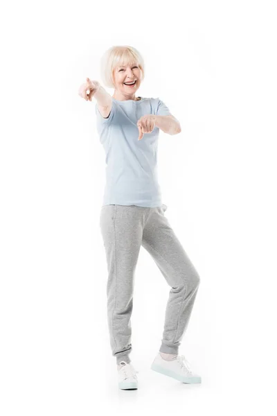 Lächelnde Seniorin im Stehen und mit den Fingern auf weiß isoliert — Stockfoto