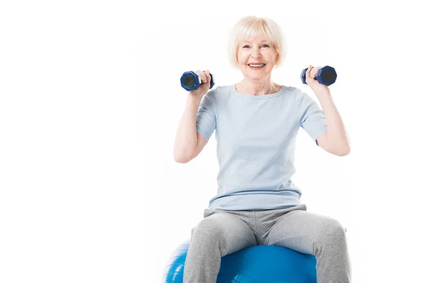 Deportista senior con mancuernas sentadas en una pelota de fitness aislada en blanco - foto de stock