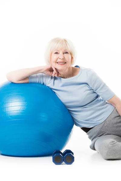 Sportiva anziana sorridente con palla fitness e manubri isolati su bianco — Foto stock