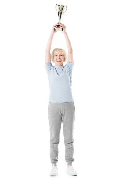 Senior sportswoman with arms up holding trophy isolated on white — Stock Photo