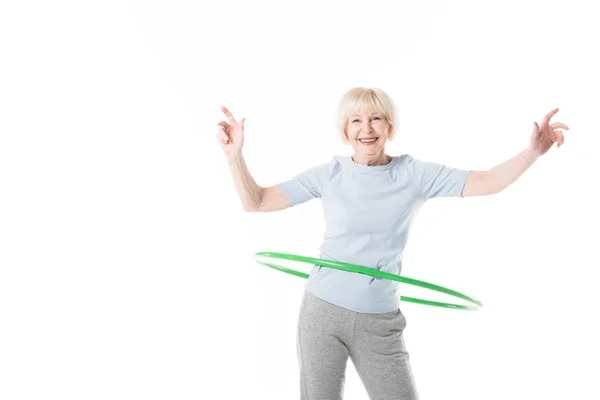 Sonriente deportista senior haciendo hula hoop ejercicio aislado en blanco - foto de stock