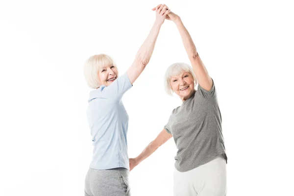 Two smiling senior sportswomen doing exercise isolated on white — Stock Photo