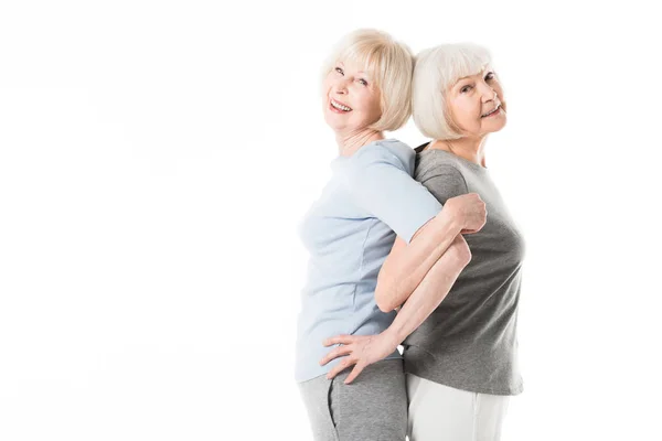 Zwei ältere Sportlerinnen, die Rücken an Rücken stehen, während sie isoliert auf weiß trainieren — Stockfoto
