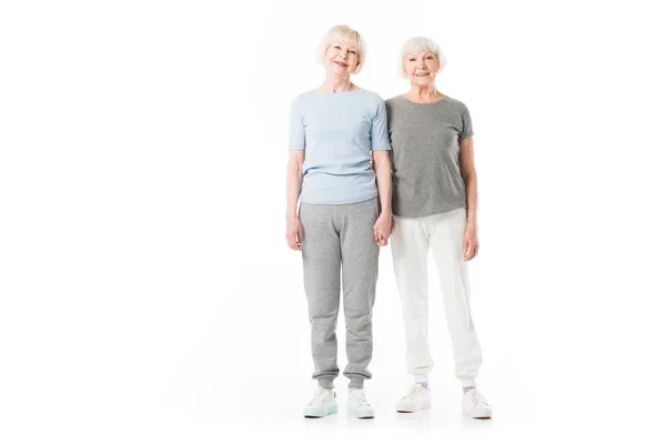 Zwei lächelnde Seniorinnen, die isoliert auf weiß stehen — Stockfoto