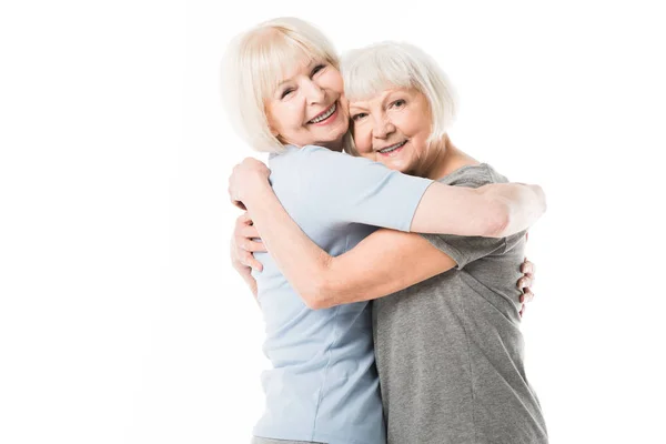 Sorrindo mulheres idosas abraçando uns aos outros isolado em branco — Fotografia de Stock