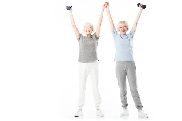 Esportistas seniores com braços para cima segurando halteres isolados em branco — Fotografia de Stock