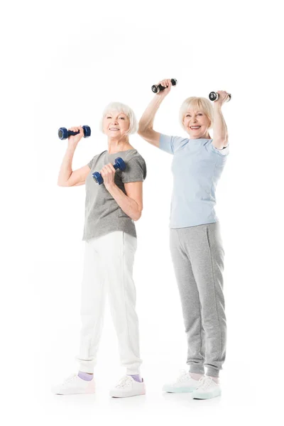 Sportives seniors souriantes faisant de l'exercice avec des haltères isolés sur blanc — Photo de stock