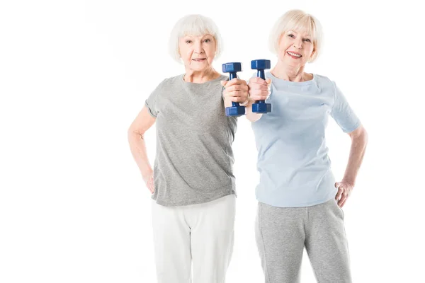 Duas esportistas seniores fazendo exercício com halteres isolados em branco — Fotografia de Stock