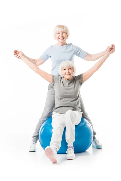 Sportives seniors souriantes avec ballon de fitness isolé sur blanc — Photo de stock