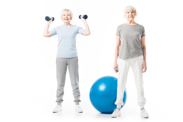 Desportistas sênior sorridentes com bola fitness e halteres isolados em branco — Fotografia de Stock