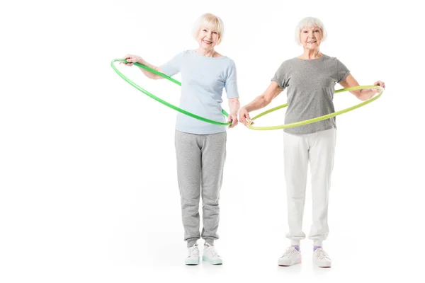 Zwei ältere Sportlerinnen beim Hula-Hoop-Training isoliert auf weiß — Stockfoto