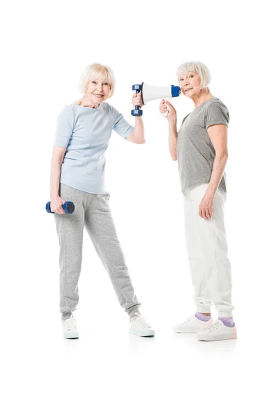 Две старшие спортсменки с гантелями и мегафоном, изолированными на белом — стоковое фото