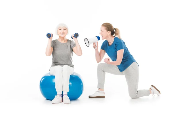 Coach with megaphone and sportswoman with dumbbells and fitness ball isolated on white — Stock Photo