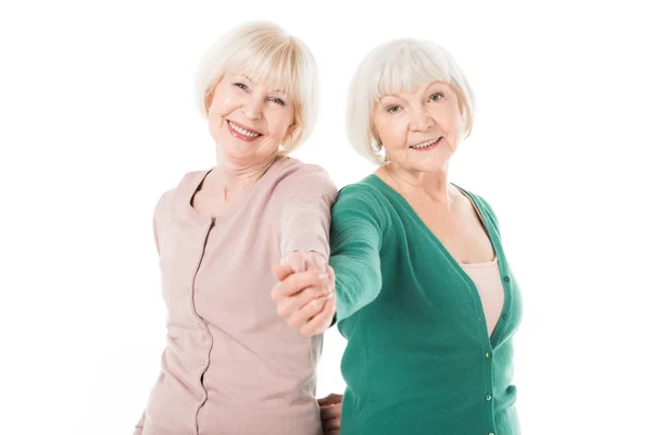 Sonrientes mujeres mayores con estilo tomados de la mano aislados en blanco - foto de stock