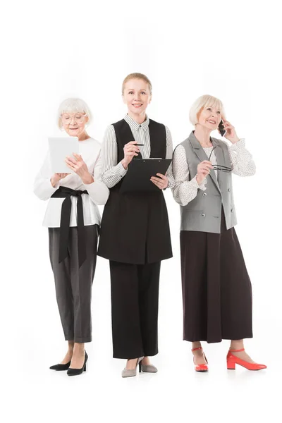 Three stylish businesswomen with digital tablet, smartphone and clipboard isolated on white — Stock Photo