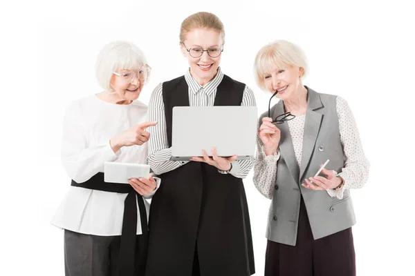 Tres elegantes empresarias con portátil, tableta digital, smartphone y gafas aisladas en blanco - foto de stock