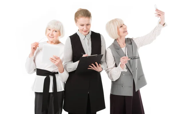 Trois femmes d'affaires élégantes avec tablette numérique, presse-papiers et smartphone isolés sur blanc — Photo de stock