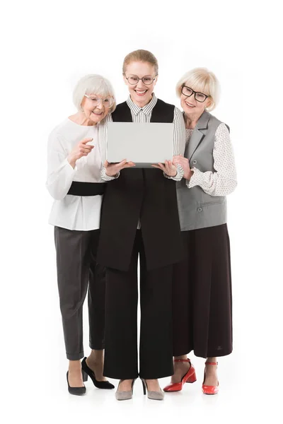 Mulheres de negócios elegantes em óculos olhando para laptop isolado em branco — Fotografia de Stock