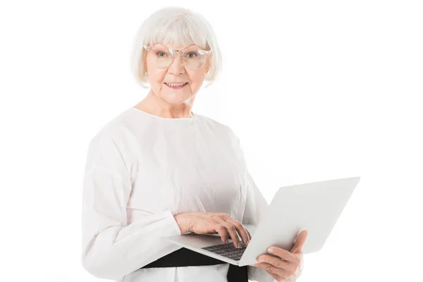 Stylish senior businesswoman in eyeglasses using laptop isolated on white — Stock Photo