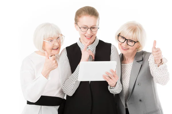 Три стильні бізнес-леді в окулярах дивляться на цифровий планшет ізольовані на білому — стокове фото