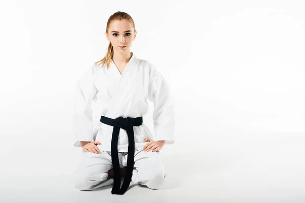 Luchadora de karate sentada y mirando la cámara aislada en blanco - foto de stock