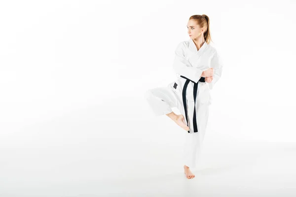 Karate-Kämpferin steht auf einem Bein isoliert auf weiß — Stockfoto