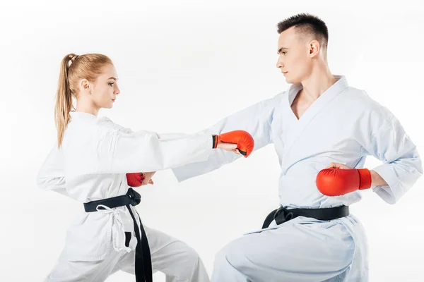 Vista lateral de los combatientes de karate entrenando en kimono y guantes rojos aislados en blanco - foto de stock