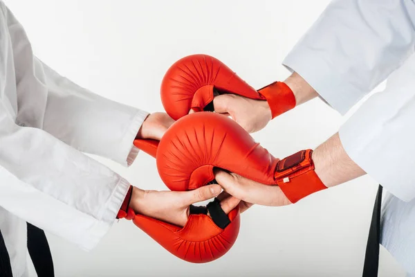 Imagen recortada de combatientes de karate tomados de la mano con guantes aislados en blanco - foto de stock