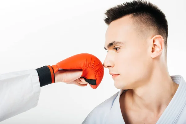 Imagem cortada de lutador de karatê olhando para a mão em luva na frente do rosto isolado no branco — Fotografia de Stock
