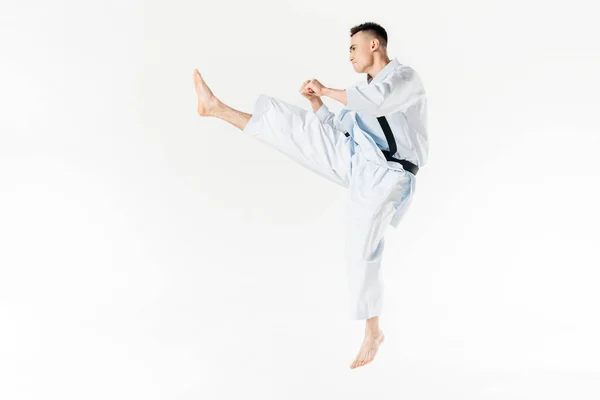 Vista lateral del entrenamiento de karate masculino aislado en blanco - foto de stock