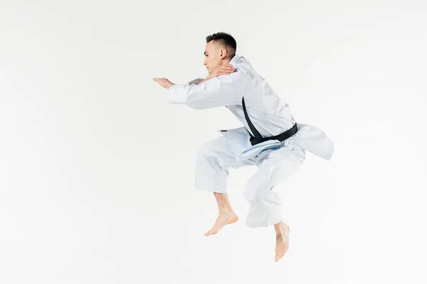 Вид збоку чоловічий карате боєць стрибає ізольовано на білому — стокове фото