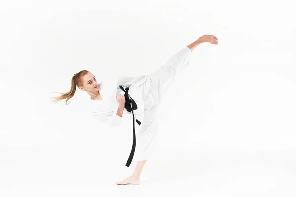 Female karate fighter with black belt performing kick isolated on white — Stock Photo