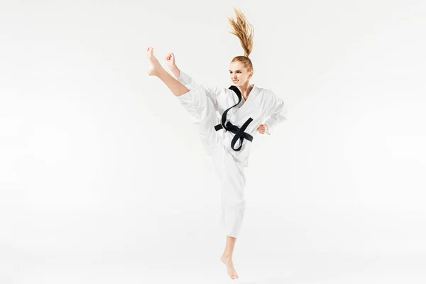 Female karate fighter performing kick isolated on white — Stock Photo